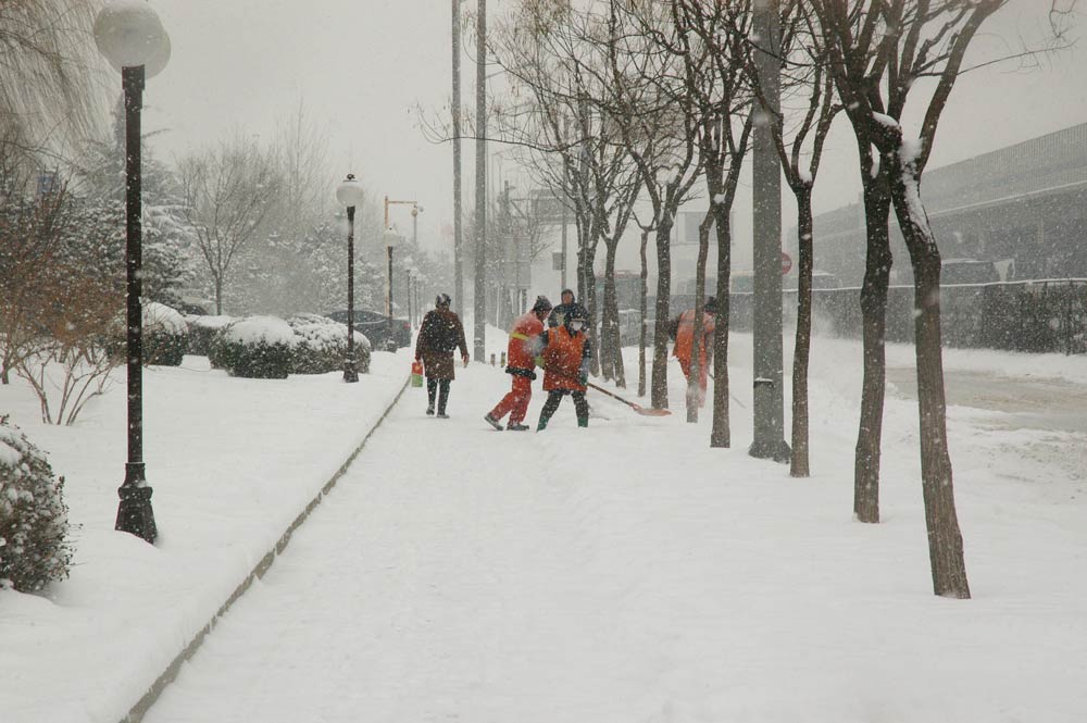 Workers in Hi Vis Winter workwear shovelling snow