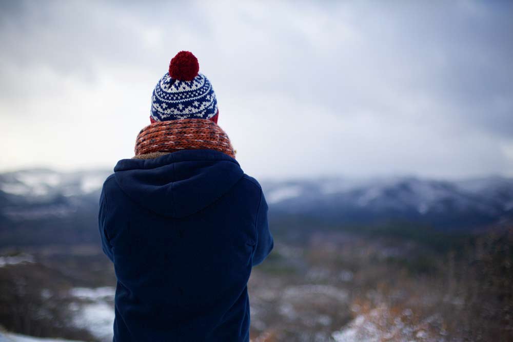 Person wearing winter accessories, hat and scarf in nature