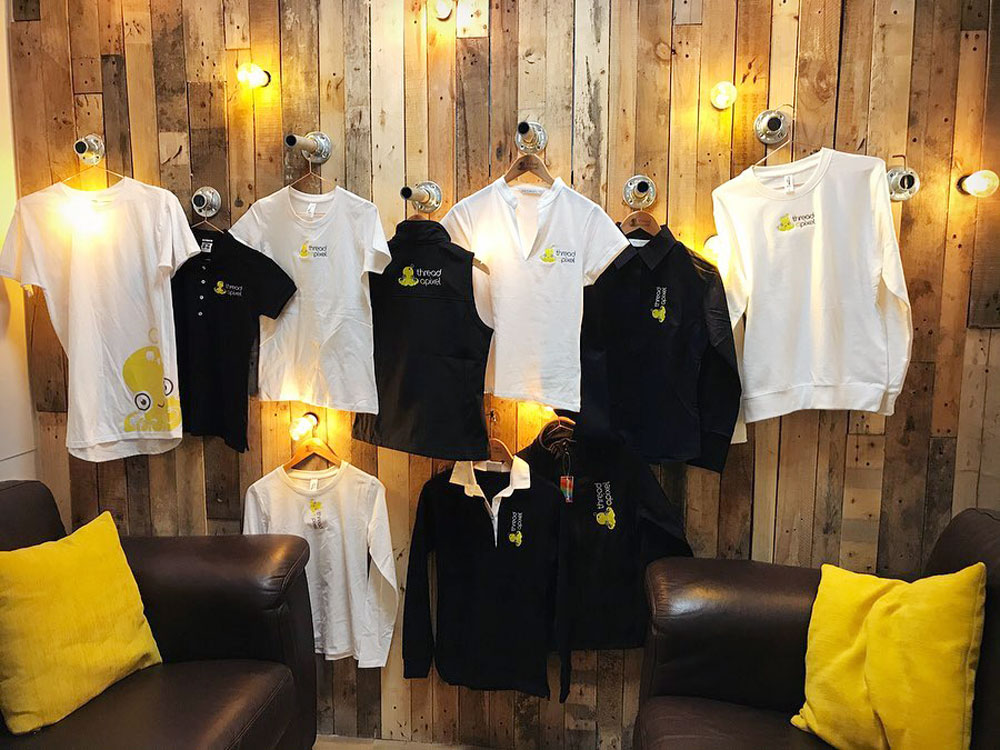 Company uniform hanging in a row with embroidered logos